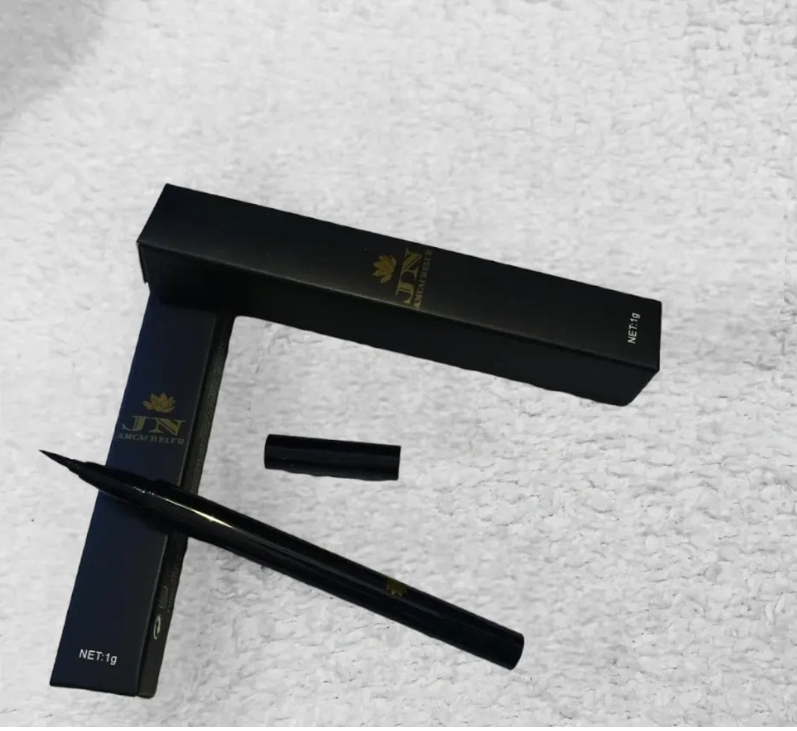 Black JNA eyeliner liquid pen resting on its box.